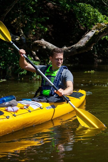 A person kayaking on a yellow raft in a river surrounded by greenery. 2