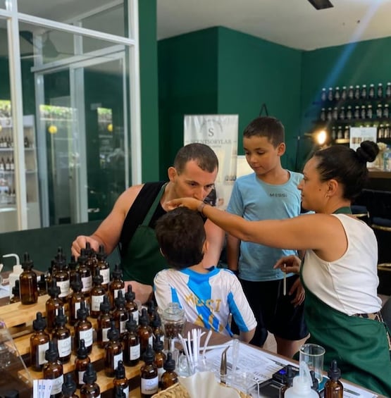 A person demonstrating the use of essential oils to a child and an adult at a counter with various bottles. 3