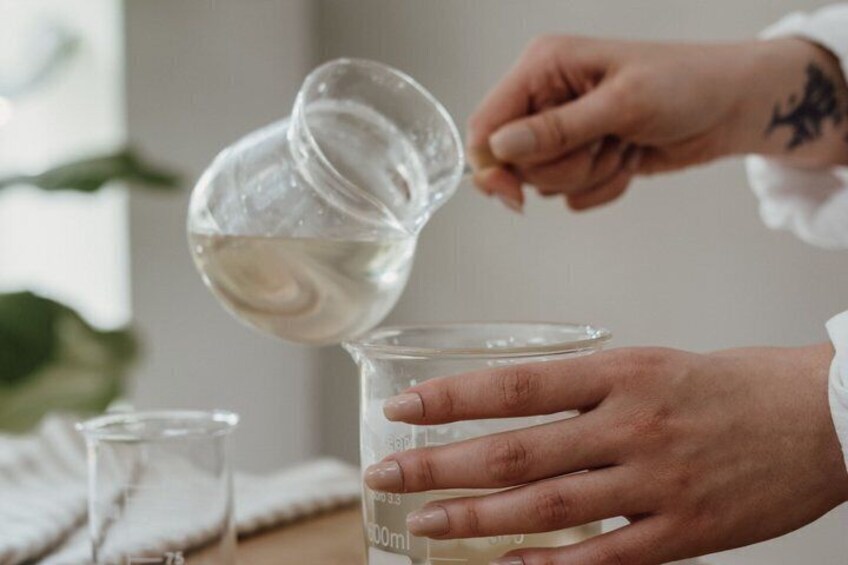 A person pouring a clear liquid into a measuring cup. 3