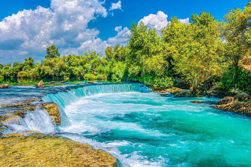 A turquoise river flowing through a forest with a waterfall. 1
