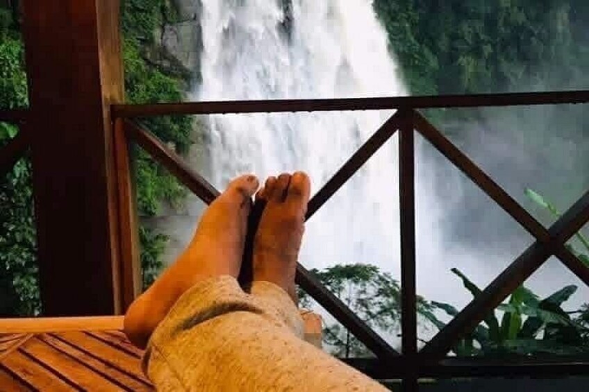 A person's feet resting on a wooden deck with a waterfall in the background. 4