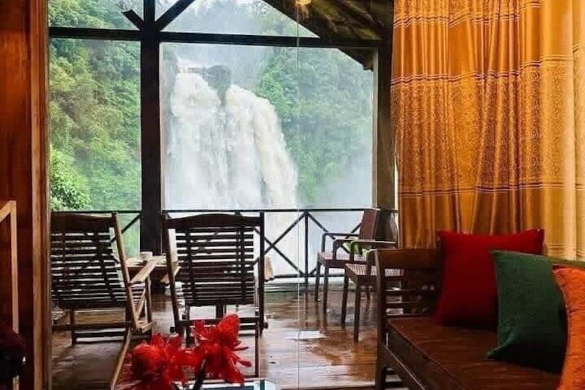 A wooden deck with chairs and a sofa overlooking a waterfall. 5