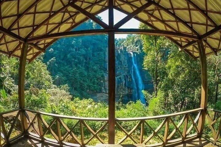 A wooden gazebo with a view of a waterfall and lush greenery. 3