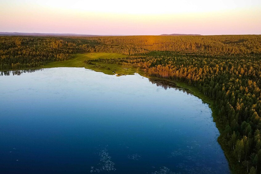 Kirkkaan taivaan alla sijaitseva järvi, jonka ympärillä on tiheä metsä. 5