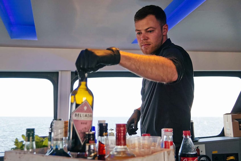 A person pouring a drink from a bottle onto a bar counter. 5