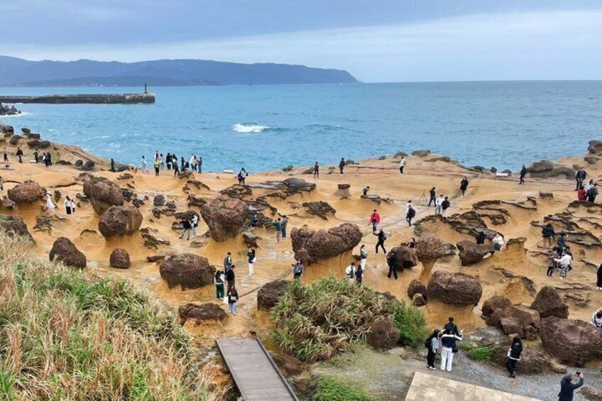 A rocky coastal area with people walking and standing on the rocks. 5