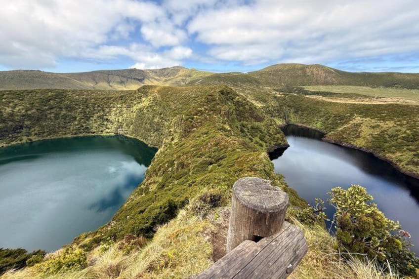 A lake surrounded by hills, a wooden post, and a clear sky. 3