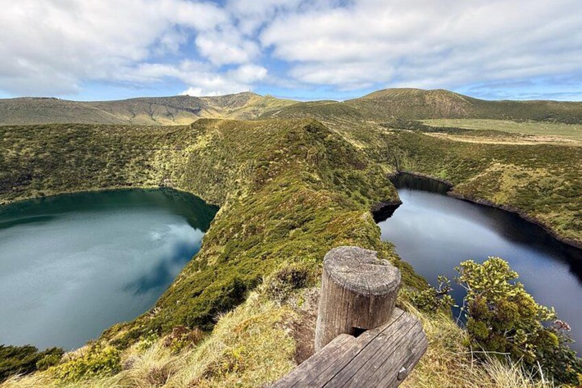 A lake surrounded by hills, a wooden post, and a tree stump. 3