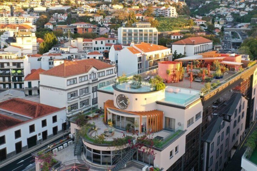 A cityscape with a prominent building featuring a clock, surrounded by other residential and commercial structures. 3