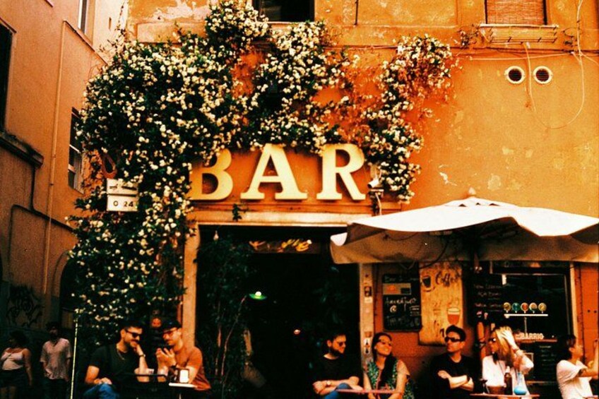 A bar with outdoor seating, a large sign, and people dining. 3