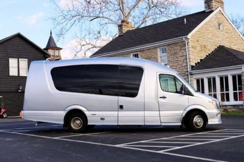 A silver van parked in a parking lot with stone buildings in the background. 2
