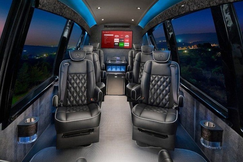 A luxurious vehicle interior with two black leather seats, a central console, and a large screen displaying information. 2