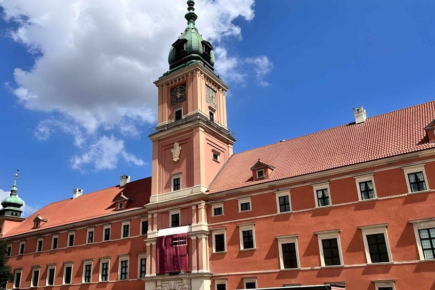 A historic building with a clock tower, red tiled roof, and a clear blue sky. 4