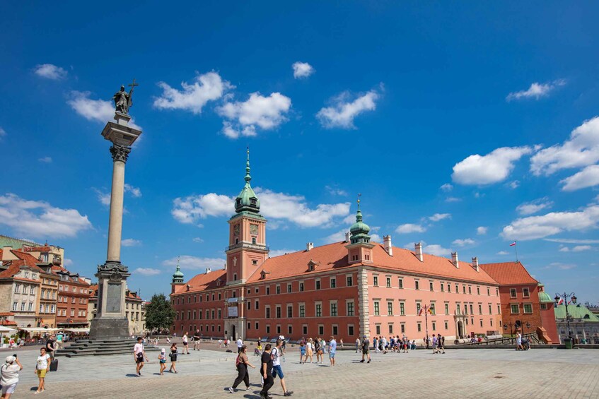 A historic building with a central monument, a clear blue sky, and a bustling public square. 2