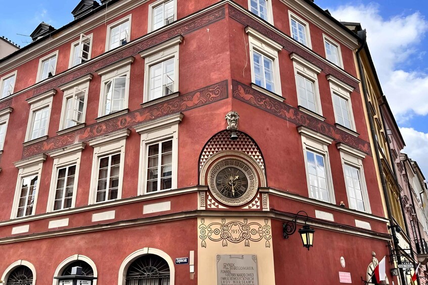 A red building with ornate decorations, a clock, and a plaque commemorating an event in 1953. 5