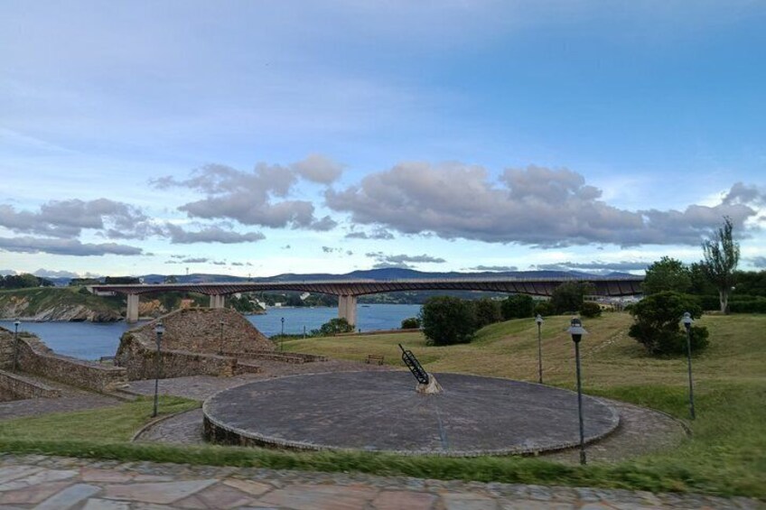 A circular plaza with a fountain, a stone structure, and a bridge in the background. 4