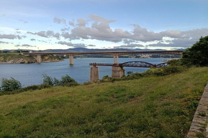 A river with a bridge, grassy banks, and distant hills. 5