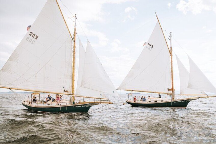 Two sailboats with large white sails on a body of water. 3