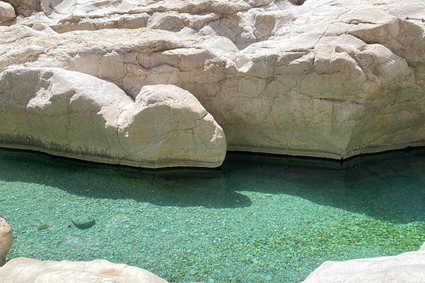 A large rock formation with clear water beneath. 4