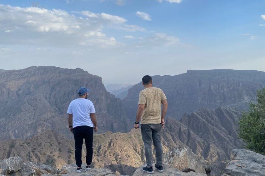 Two people standing on a rocky outcrop overlooking a canyon. 1