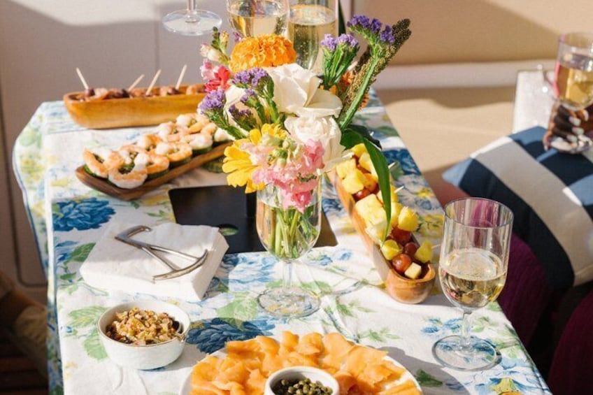 A table with food, drinks, and a floral centerpiece. 4