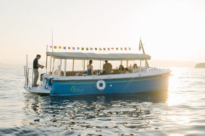 A blue boat with a canopy, people on board, and a flag. 1