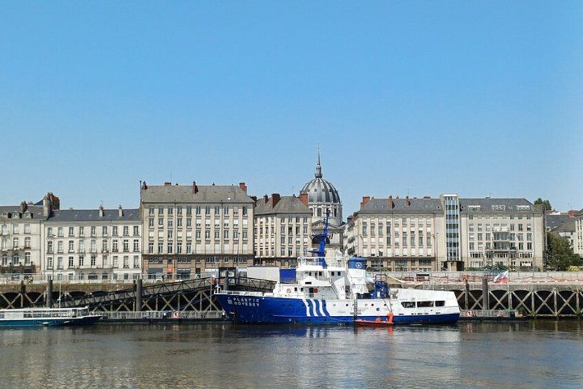 A large blue and white ferry docked at a pier with a historic building in the background. 2