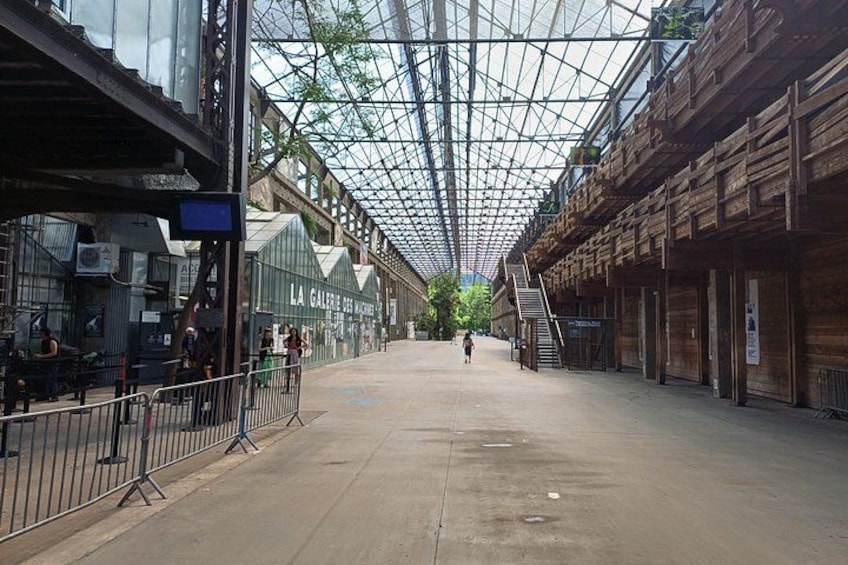 An indoor pedestrian area with a glass ceiling, wooden structures, and a staircase. 4