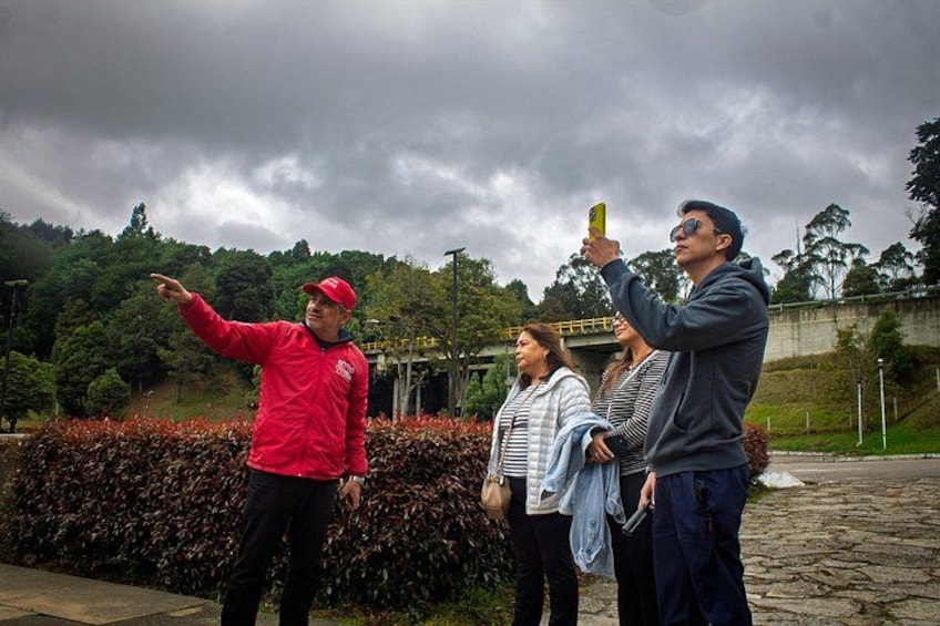 A person in a red jacket pointing, a person in a blue jacket taking a photo, and two others standing nearby. 1