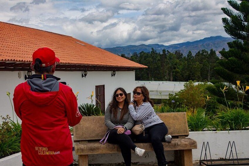 A person in a red jacket taking a photo of two people sitting on a bench. 4