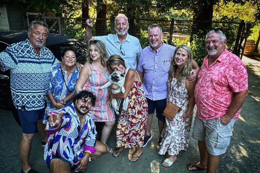 A group of people posing for a photo in an outdoor setting with trees and a fence in the background. 2