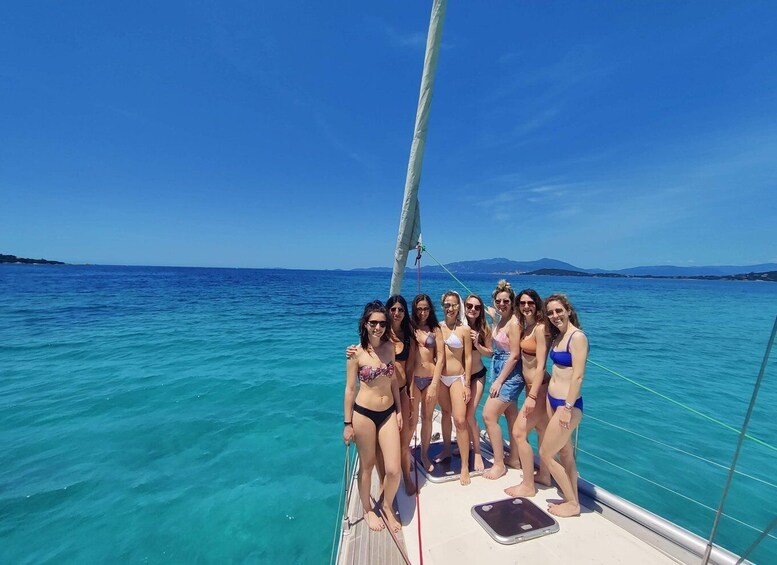 A group of people on a sailboat in clear blue waters with distant land visible. 3