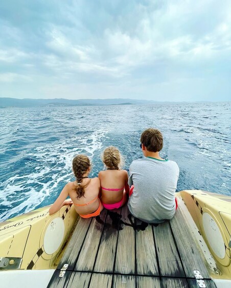 Three people on a boat with a view of the ocean and distant land. 4