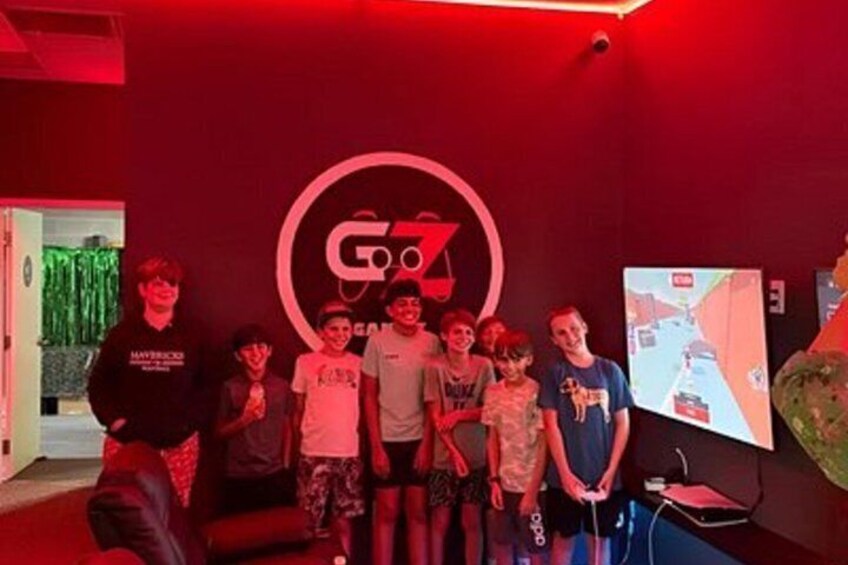 A group of people standing in front of a wall with a large logo and a screen displaying a video game. 3