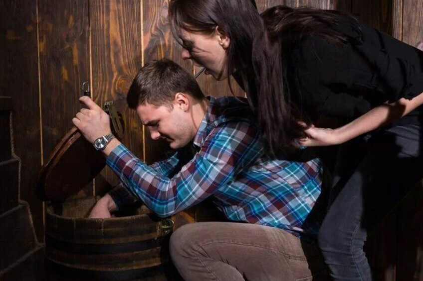 A person in a plaid shirt opening a wooden barrel. 1