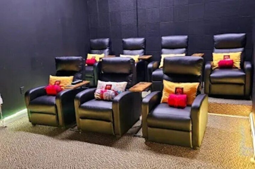 A room with multiple black massage chairs, each with a red cushion. 3
