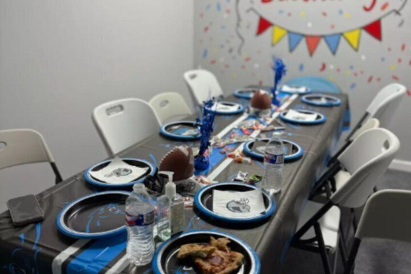 A long table set for a meal with blue and white plates, a water bottle, and a bowl of food. 1