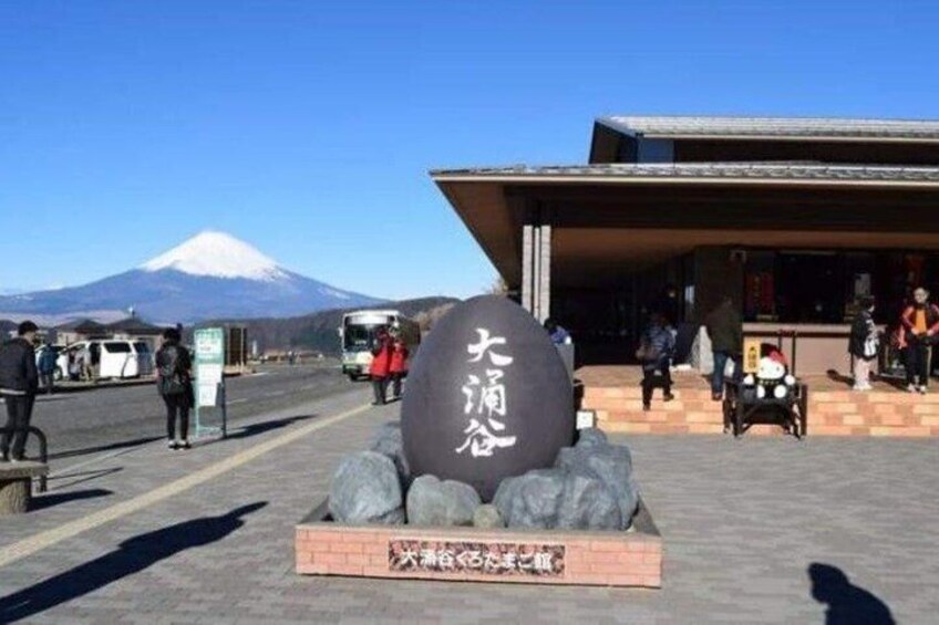 A stone monument with Japanese characters, a building with a tiled roof, and a mountain in the background. 4