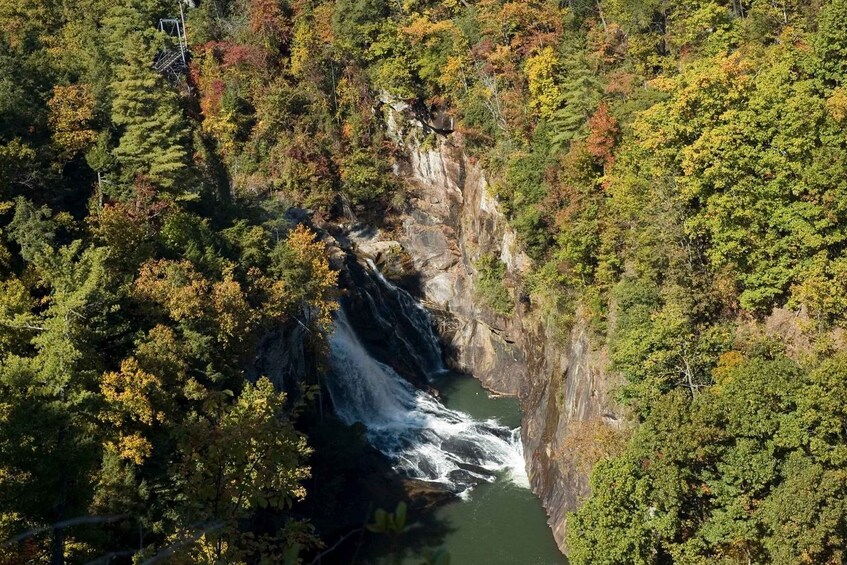 A waterfall cascading down a rocky cliff surrounded by dense forest. 2
