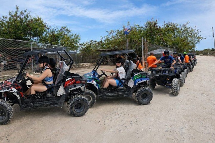 A group of people riding atv's on a dirt road. 1