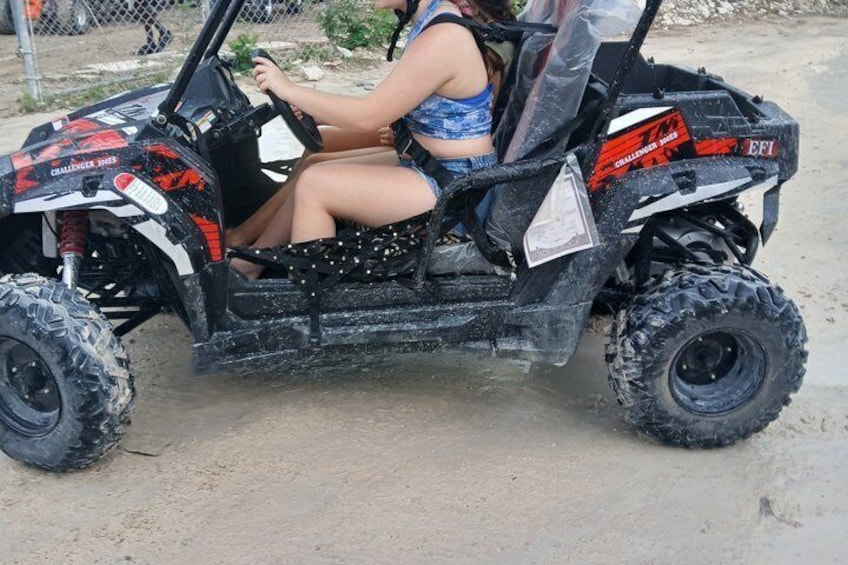 A person driving a black and red ATV on a dirt path. 2