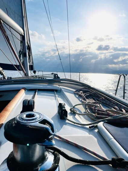 A sailboat's deck with ropes, a winch, and a wooden tiller. 3
