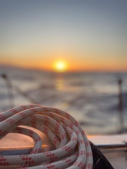 A rope with a red and white pattern, a sunset, and the ocean. 5