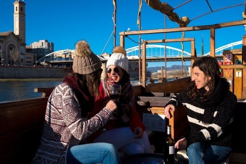 Three people on a boat with a cityscape and a bridge in the background. 4