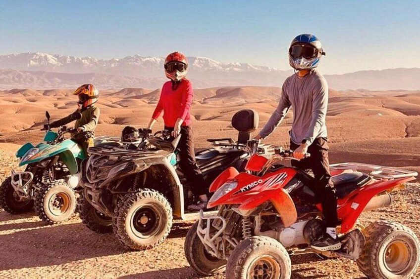 Three people on quad bikes in a desert landscape with mountains in the background. 4