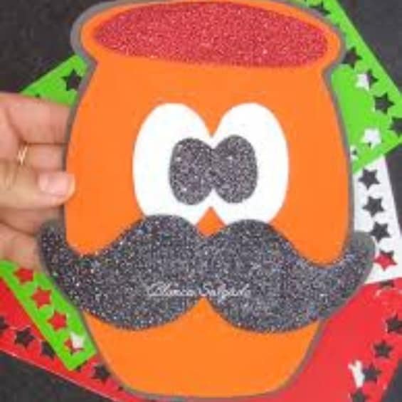 A glittery orange object with a bow tie and mustache, held by a hand. 2