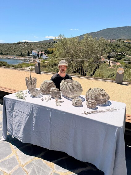 A person standing behind a table displaying various silver jewelry items. 5