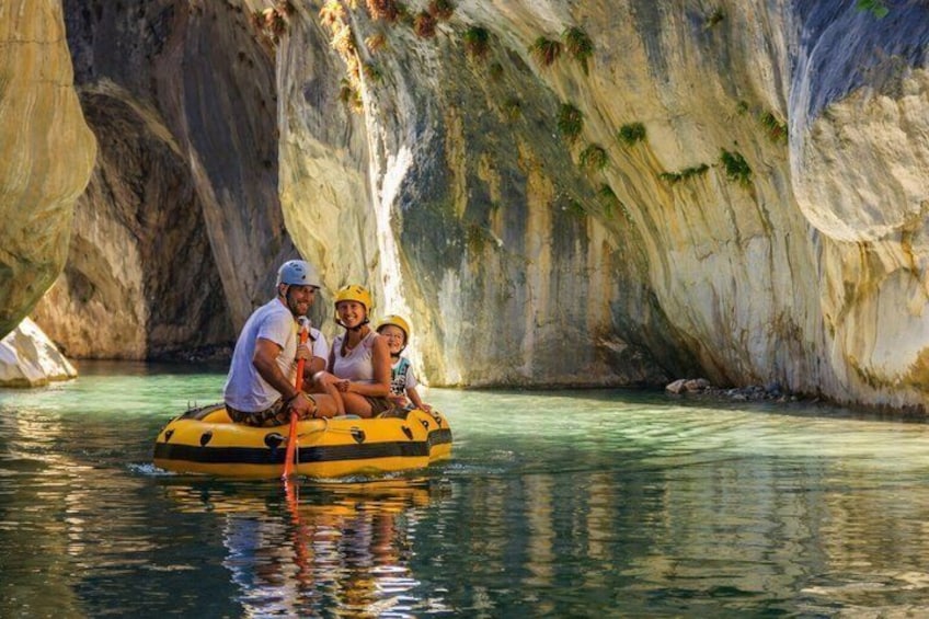A person in a yellow raft on a river with rocky cliffs. 1
