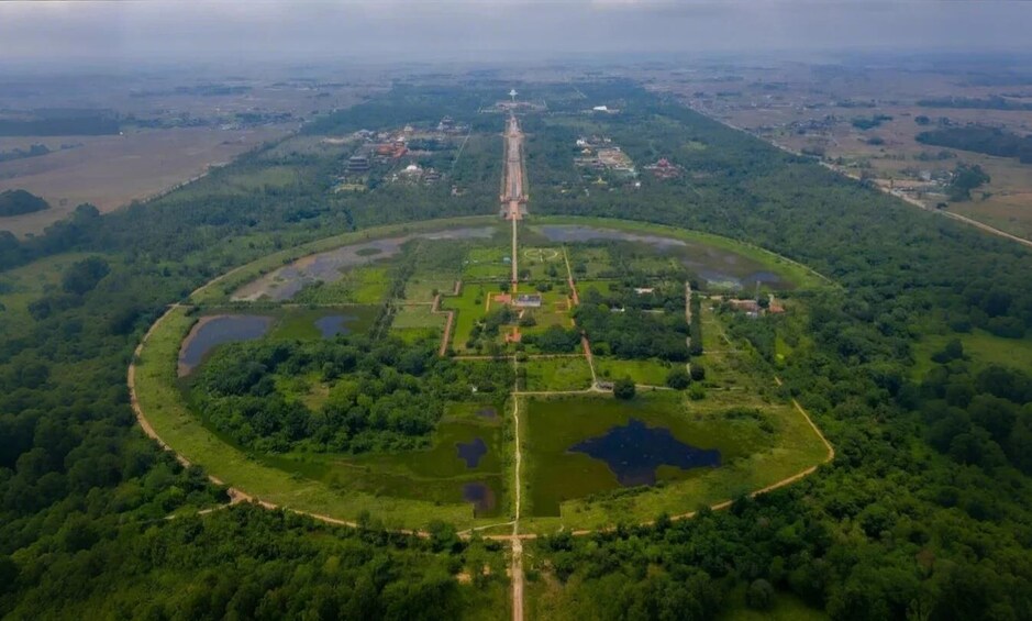 An aerial view of a circular park with a central tower, surrounded by water bodies and greenery. 4