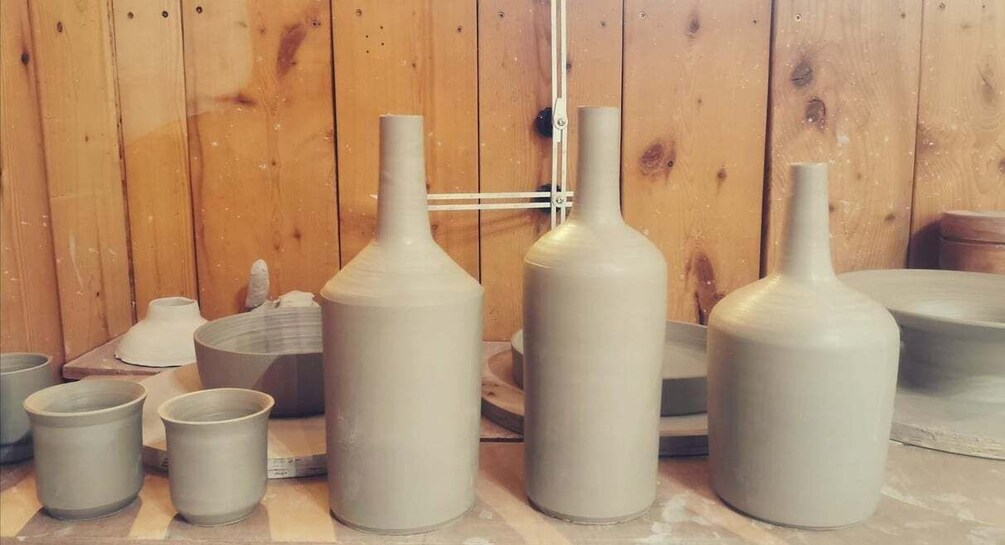 Ceramic pottery items, including vases and cups, on a workbench. 1